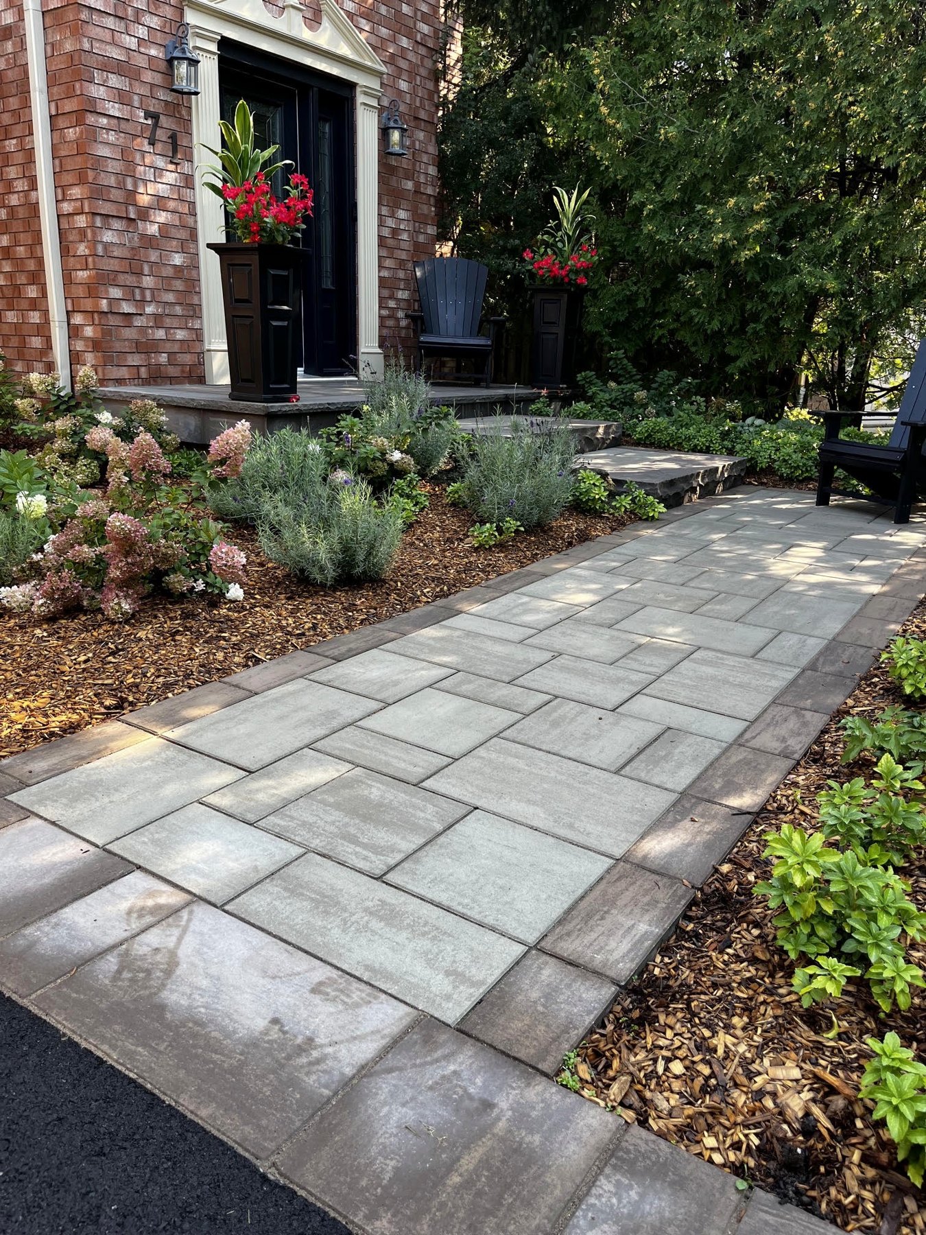 Interlock front walkway leading to natural stone steps and a planted porch entrance