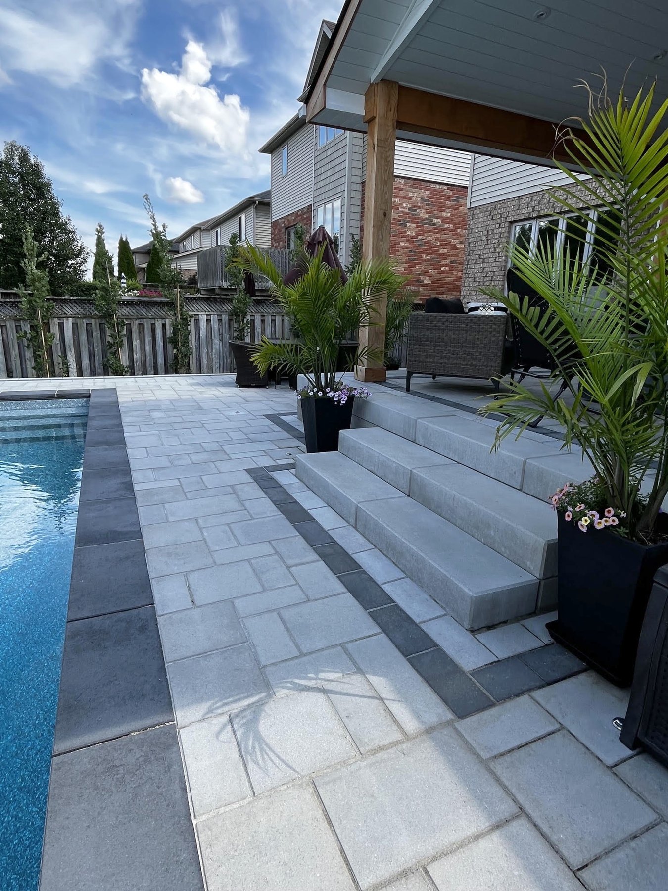 Interlock poolside patio and walkway with broad stone steps and planted containers